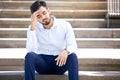 Business man, stress and outdoor on stairs with a headache, depression or burnout in city. Young Indian male Royalty Free Stock Photo