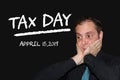 Business man stressed because of coming tax day - chalk words on black board