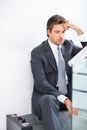 Business man stressed out. Mature business man sitting on the stairs with hand on head. Royalty Free Stock Photo