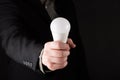 Business man in suit Holding a white light bulb in hand, isolated on gradient black background Royalty Free Stock Photo