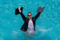 Business man in suit with laptop excited jumping in swimming pool. Summer travel tourism and business concept. Crazy Royalty Free Stock Photo