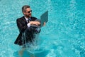 Business man in suit and laptop splash water in swimming pool. Crazy summer business vacation. Funny excited amazed Royalty Free Stock Photo