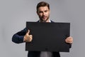 Business man in suit showing thumbs up holding promo blank board on studio background. Blank signboard with copyspace Royalty Free Stock Photo