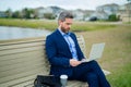 Business man in suit sitting on bench. Business man on bench in park outdoors. Thinking about business. Thoughtful Royalty Free Stock Photo