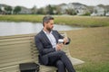 Business man in suit sitting on bench. Portrait of business man on bench in park outdoors. Thinking about business Royalty Free Stock Photo