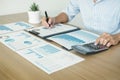 Business man in suit sitting at table working on his laptop and looking at a document on the desk Royalty Free Stock Photo