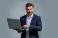 Business man in suit working on laptop in studio. Man checking email on laptop, writing message in social network, using