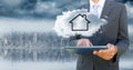 Business man with tablet and cloud with house against blurry skyline Royalty Free Stock Photo