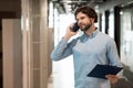 Business man talking on phone at office, holding clipboard Royalty Free Stock Photo