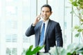 Business man talking smart phone by windows with city view, inside office building background, businessman on phone Royalty Free Stock Photo