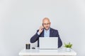 Business man teleworking from home with a laptop and talking on a cell phone. Bald man with glasses