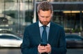 Business man texting message on smartphone near office. Royalty Free Stock Photo