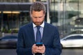 Business man texting message on smartphone near office. Royalty Free Stock Photo