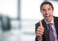 Business man thumbs up against blurry office Royalty Free Stock Photo