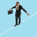 Business man on tightrope concentrate to walking isolated on blue background Royalty Free Stock Photo