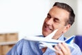 Business man, travel and toy plane for flight, vacation and holiday planning with a smile at home. Happy, airplane model