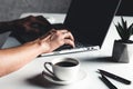 A man types on a laptop, business concept, glasses, a cup of coffee and a pen on a gray background. Royalty Free Stock Photo