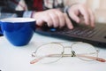 Business man using laptop computer and hand typing on laptop keyboard with notebook pen glasses and cup of hot coffee Royalty Free Stock Photo