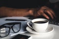 A man types on a laptop, business concept, glasses, a cup of coffee and a pen on a gray background. Royalty Free Stock Photo