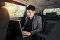 Business man using laptop computer while sitting in the back seat of car Royalty Free Stock Photo
