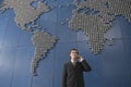 Business man using mobile phone in front of world map in office Royalty Free Stock Photo