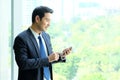 Business man using smart phone by windows with city view, inside Royalty Free Stock Photo