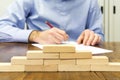 Business man and wall built with small wooden blocks