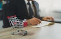 Business man wearing suit and calculates the budget. Shopping cart a on table with note book. Budget of poor low income family. Royalty Free Stock Photo