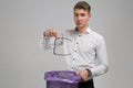 Young man throws glasses in trash isolated on white background