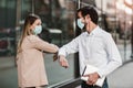Business man and woman with safety masks greeting with elbow bump