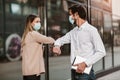 Business man and woman with protective masks greeting with elbow bump in front of office building Royalty Free Stock Photo