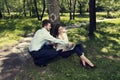Business man and business woman sitting under the tree smiling and working on a laptop in a public city park Royalty Free Stock Photo