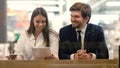 Business man and woman sitting using tablet in a mall. Royalty Free Stock Photo