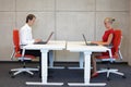 Business man and woman working in correct sitting posture with laptops sitting on chairs