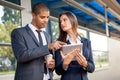 Business man and woman working outdoors with tablet computer in Royalty Free Stock Photo
