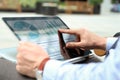 Business man working and analyzing financial figures on a graphs on a laptop outside