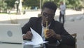 Business man works in outdoor coffee shop with his laptop and wireless internet connection, drinking juice Royalty Free Stock Photo