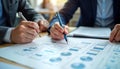 Business managers review disaster recovery workflows in formal meeting. Write notes on printed documents. Meeting focuses on