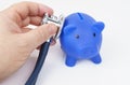 On a white background, a blue piggy bank. A man listens to a piggy bank with a stethoscope. Royalty Free Stock Photo