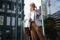 Happy succesful business woman wearing eyeglasses and classic wear talking on mobile phone and smiling while standing