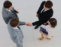 Business meeting. Top view of four people in formalwear standing close to each other while two of them handshaking. Royalty Free Stock Photo