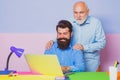 Business men team of two people talk and work together on laptop. Old father and young man looking at laptop screen Royalty Free Stock Photo