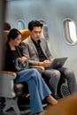 Business man use laptop and discuss with his co-worker who sit beside on the airplane during go to work with the project in other Royalty Free Stock Photo