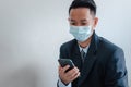 Business men wear face masks to watch mobile phones