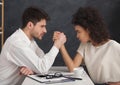 Business man and woman armwrestling in office