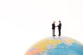 Business miniature people handshaking on the globe