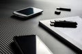 2 Business Mobiles With Reflections And An USB Drive Lying Next To A Blank Tablet With USB Drive On Top, All Above A Carbon Layer