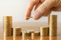 Business, Money, Finance, Secure and Saving Concept. Close up of man hand holding and put a coin to stack of coins on wooden table Royalty Free Stock Photo