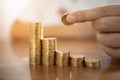 Business, Money, Finance, Secure and Saving Concept. Close up of man hand holding and put coin to stack of gold coins on wooden Royalty Free Stock Photo