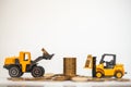 Business, Money and Financial Concept. Closeup mini forklift and loader truck mini car toy model contain coins to stack of gold